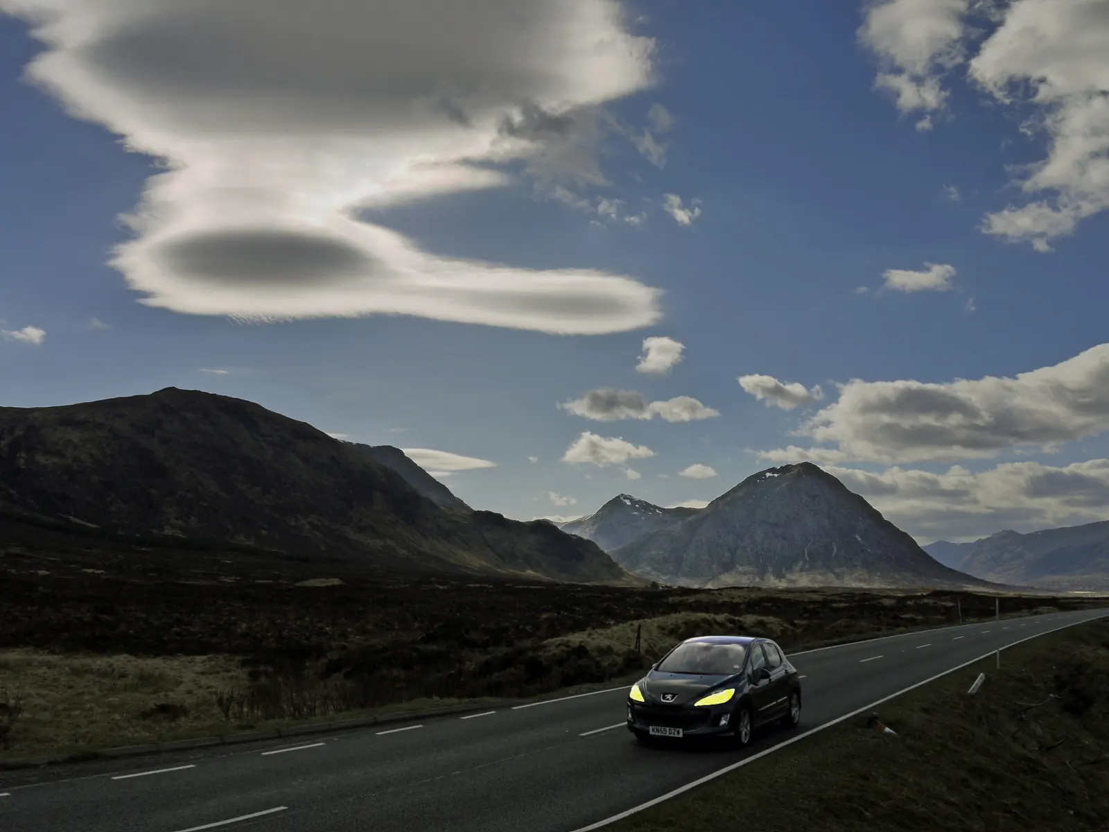 A car on the empty road through Glen Coe beneath Buachaille Etive Mòr