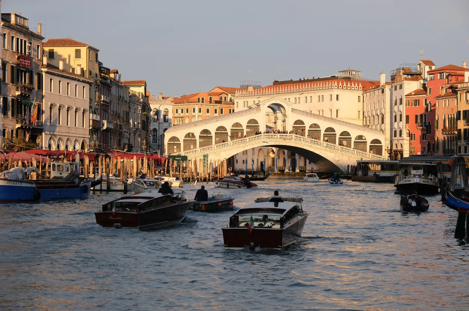 Water taxis on the Grand Canal approaching the Rialto Bridge at golden hour